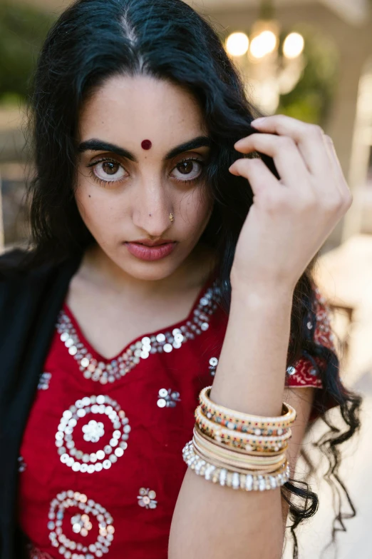 woman in red and black blouse holding up three celets