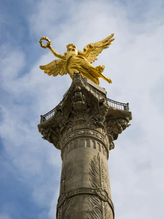 a golden angel statue is atop an ornately styled building