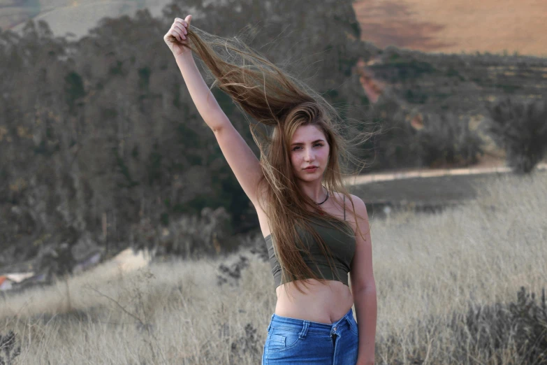 a woman standing in a field holding her hair in the wind