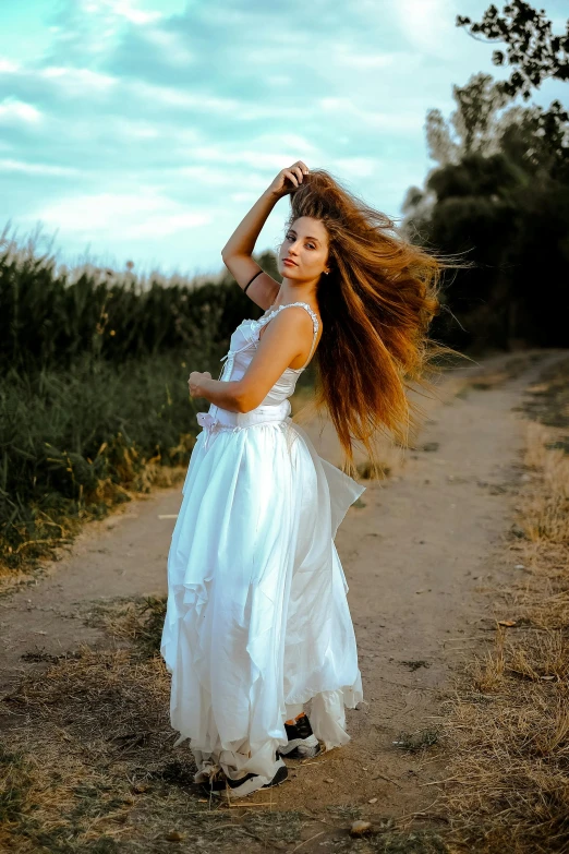 young woman wearing long white dress on dirt path