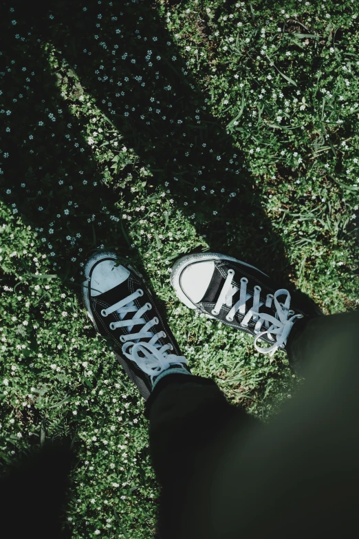 the shadow of a person with sneakers in grass