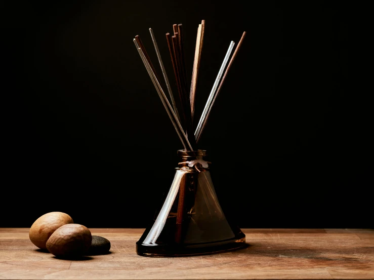 a metal vase containing candles, sticks and an object