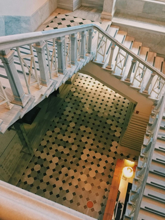 the inside of a staircase with an iron railing and patterned floor