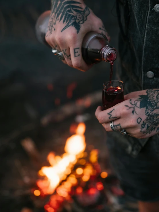 a tattooed man is preparing soing by the fire