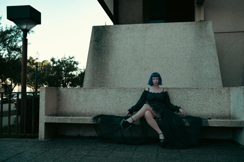 a woman sits on a ledge with her shoes in her hand and the clothes hanging in front of her