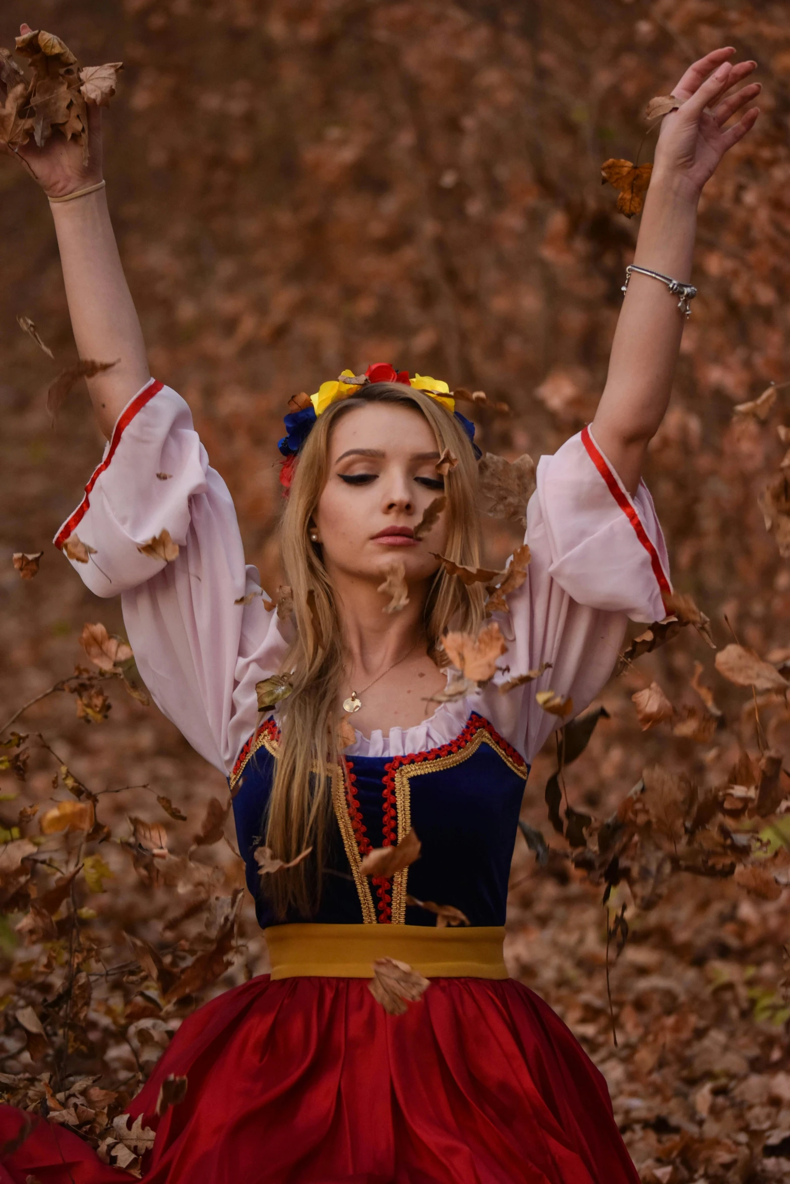 a beautiful young woman dressed in costume standing outdoors in leaves