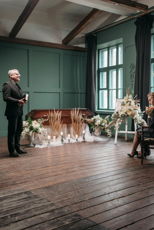 a woman sitting in a chair as a man stands next to her