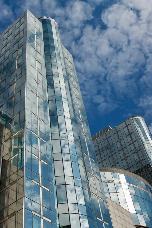 a very tall building with windows that are reflecting the sky