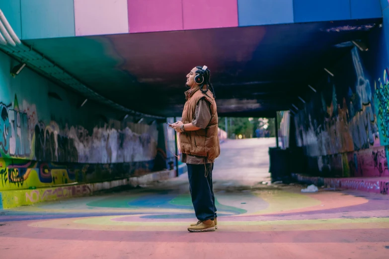 a man standing outside in front of a multicolored wall