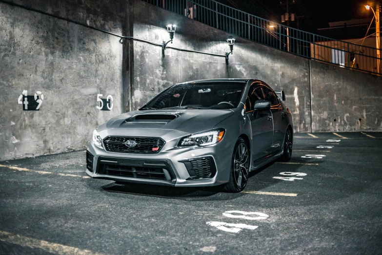 a silver car is parked on a parking lot at night