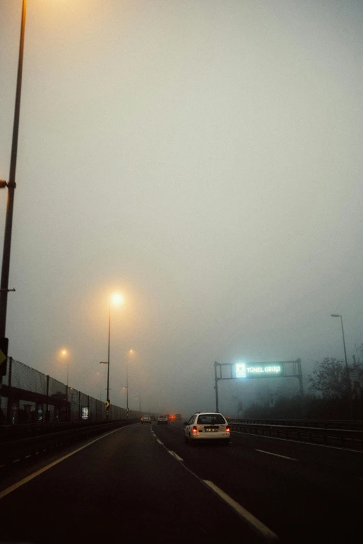 a car on a road with fog and street lights