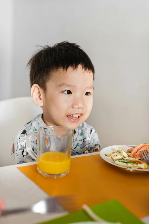 a little boy with a plate of food at a table