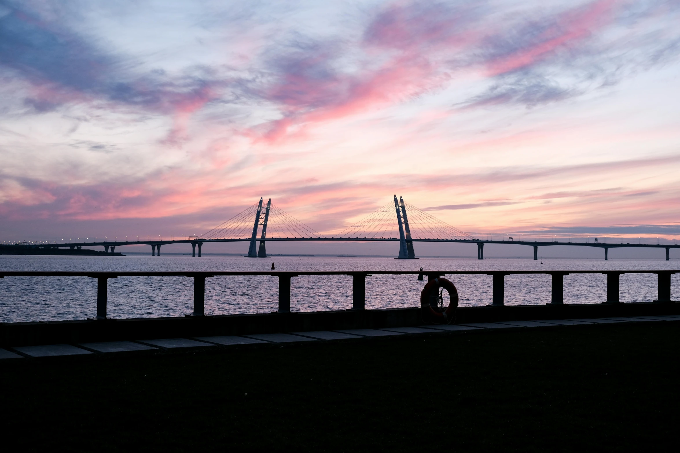 a man riding his bicycle on a bridge beside the ocean at sunset