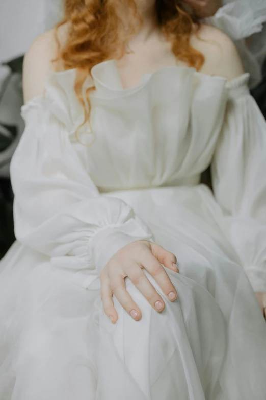 a woman in a white wedding dress holding a pink ring