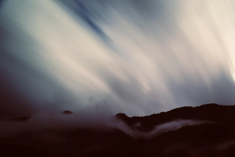 a group of clouds hovering over the top of a mountain