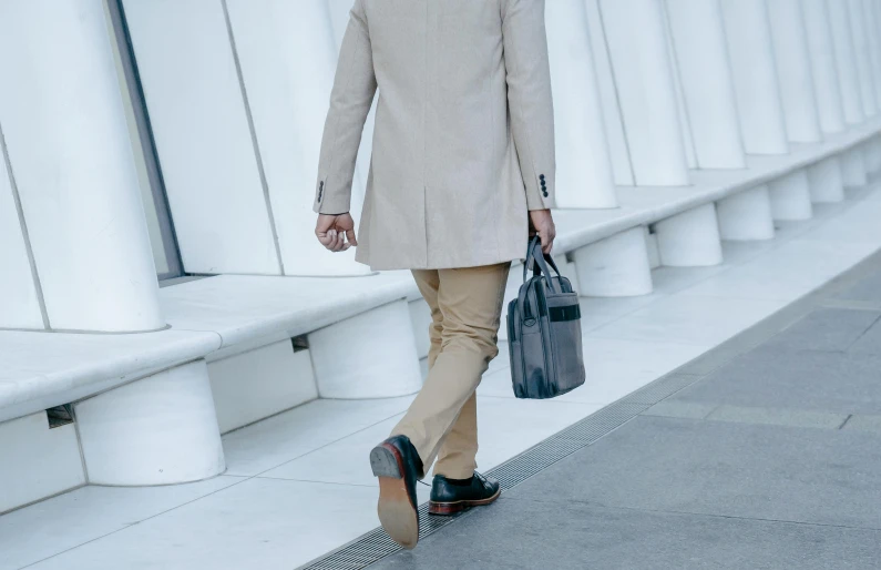 a man with a suit and tie on walks down the sidewalk