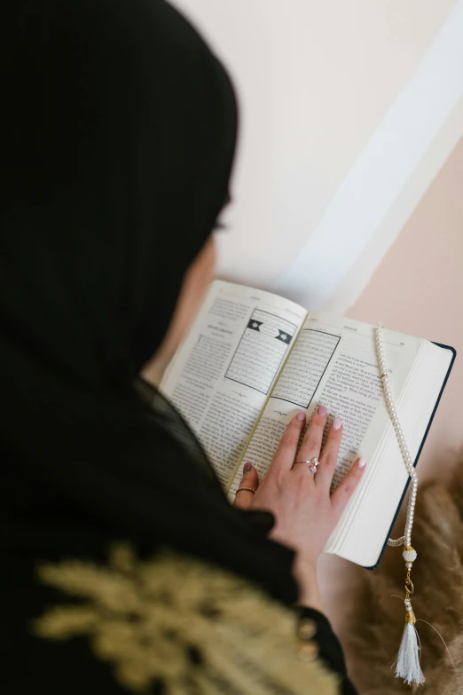 a woman in hijab is reading a book