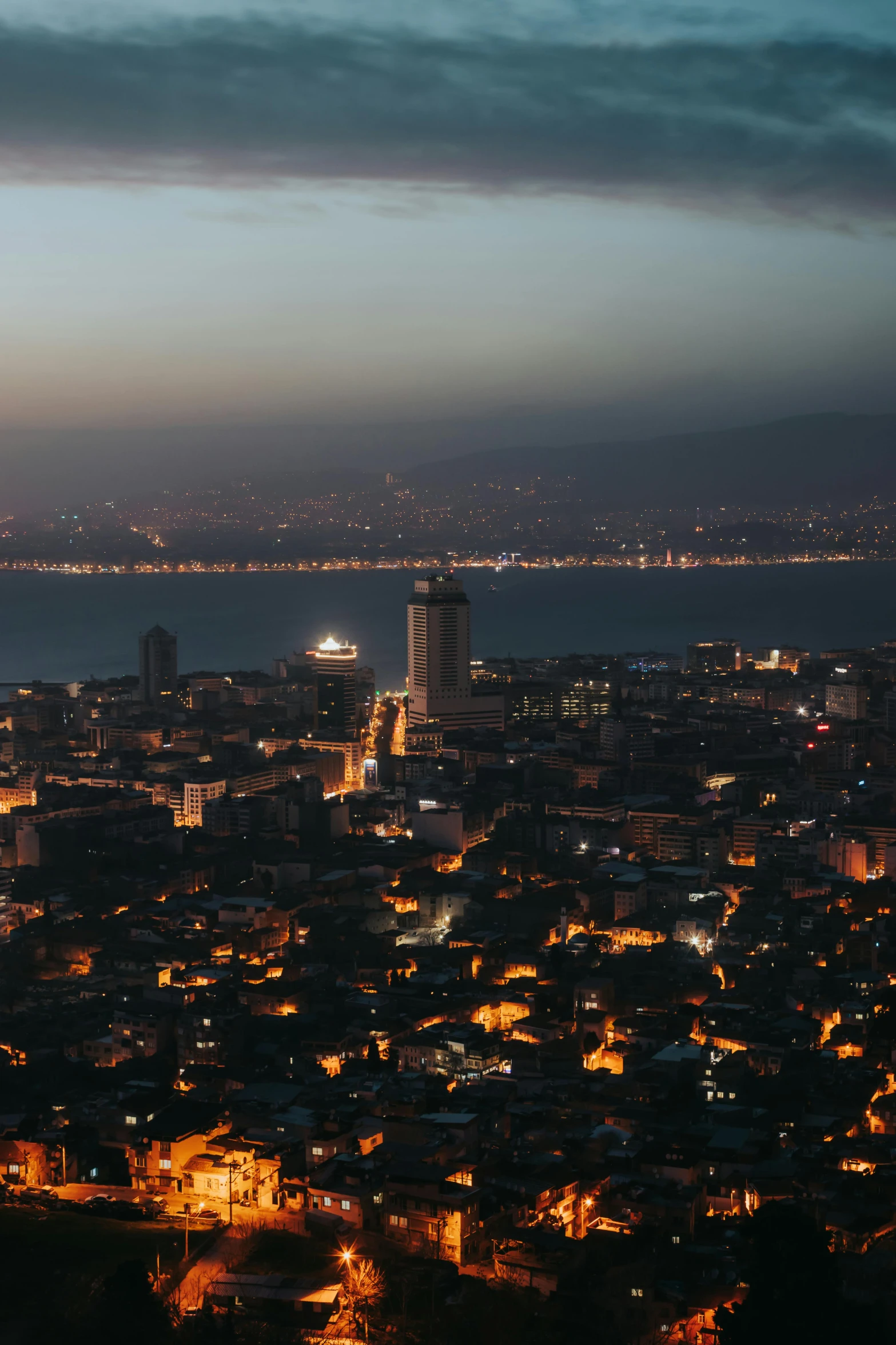 a city with a tower at night next to a lake