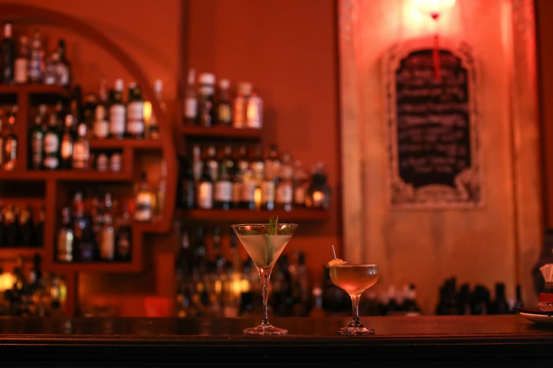 two glasses on a bar that are holding martinis