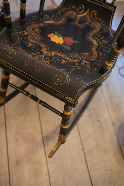 a black wooden chair with an orange rose design