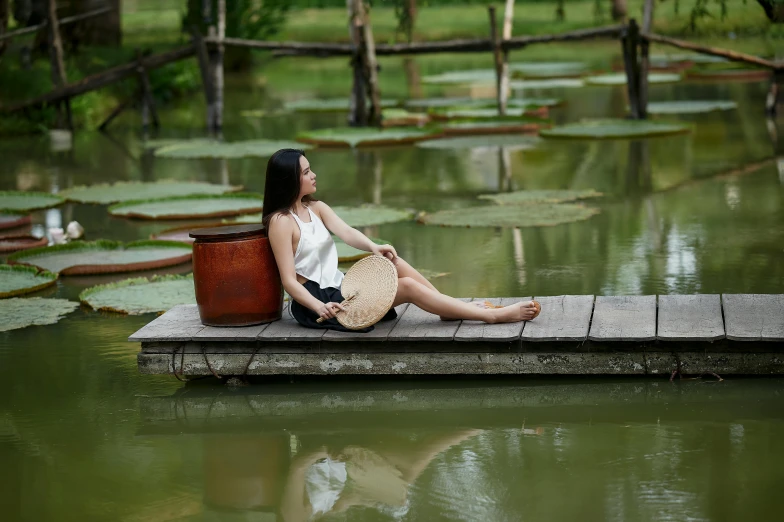 a woman sitting on a platform next to a body of water