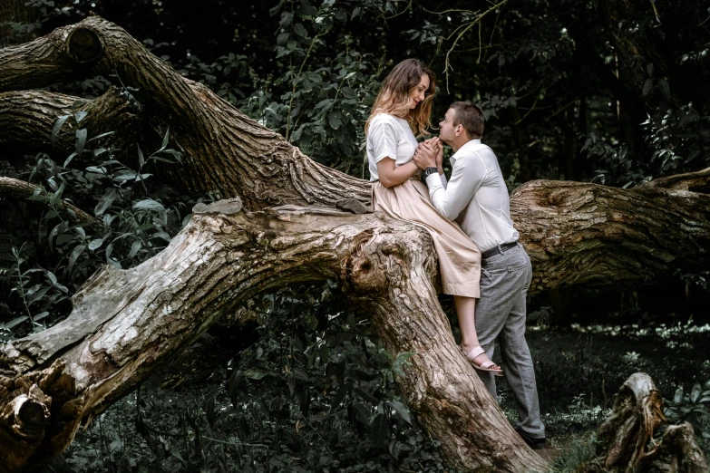 a couple sitting on a tree nch surrounded by trees