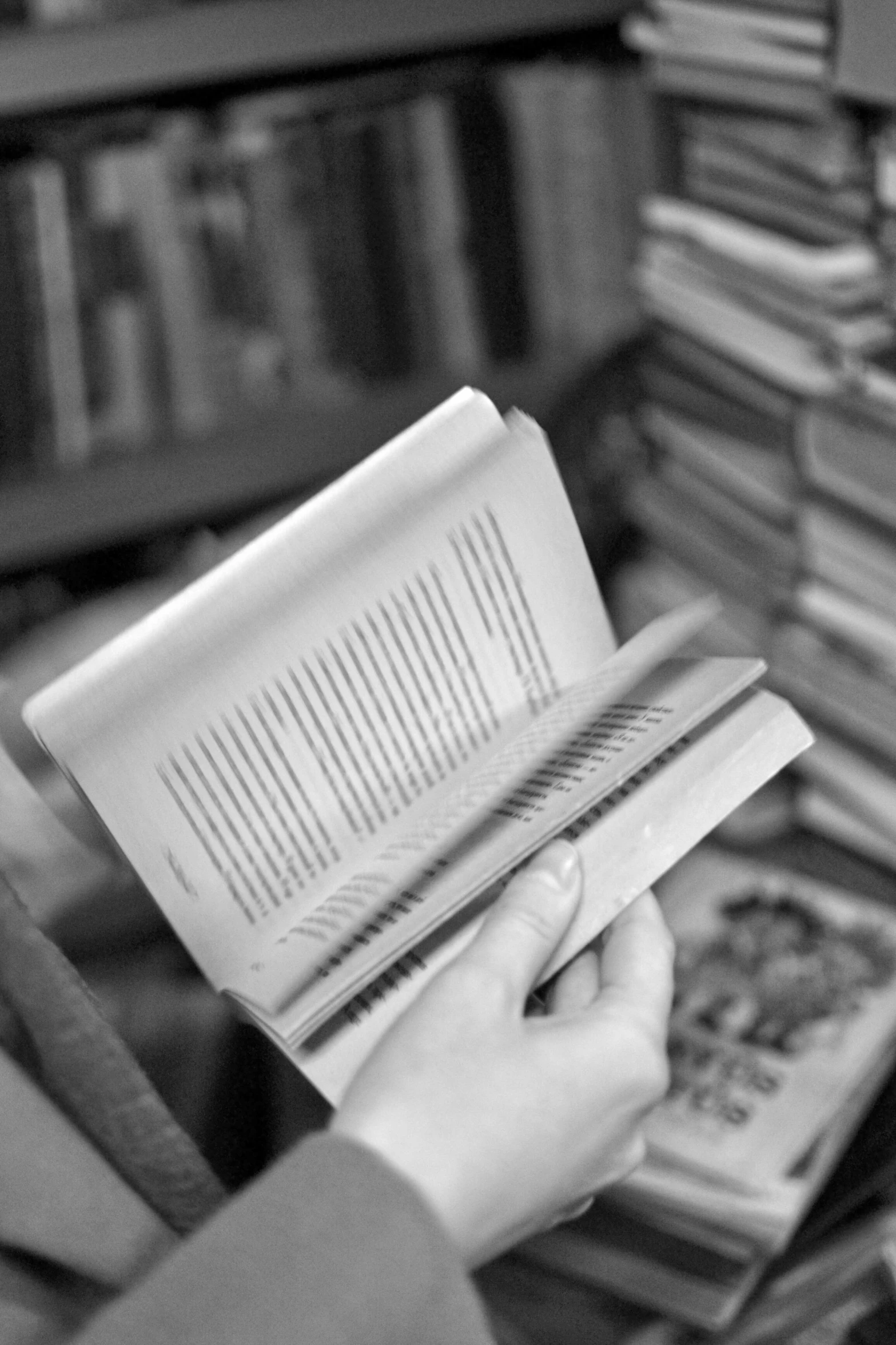 person reading a book in front of a bookshelf