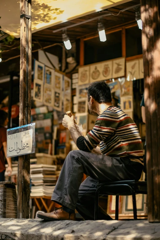 a man sitting on a stool outside of a book store