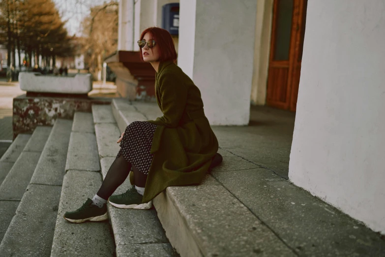 a person is sitting on the ledge of the sidewalk