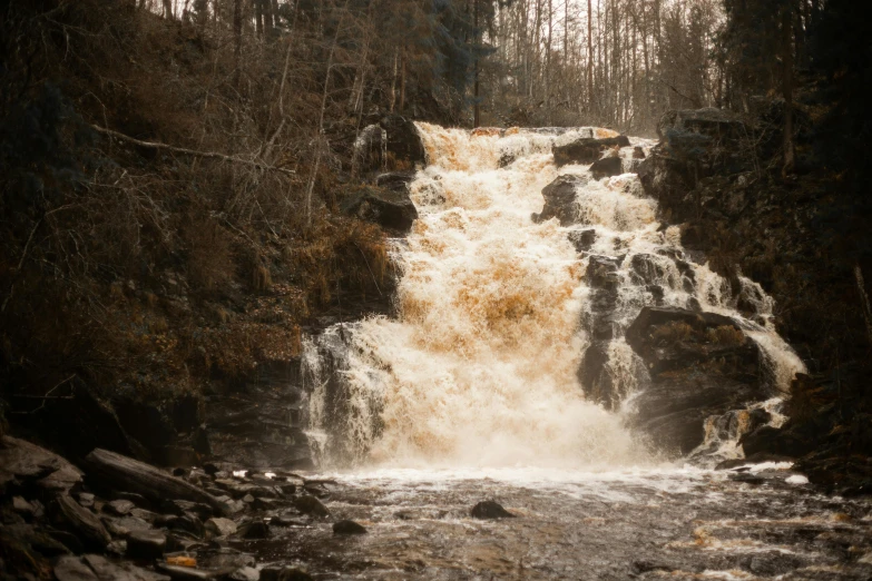 a waterfall surrounded by rocks and water with water cascading down it