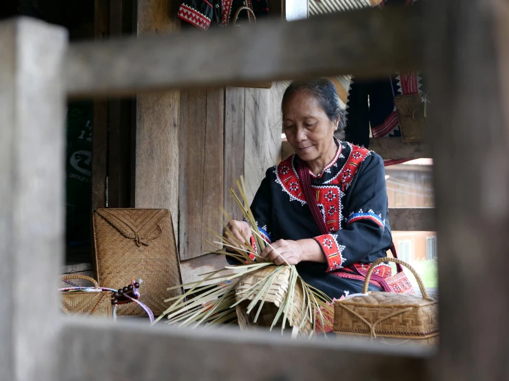 an asian woman sitting down next to a basket