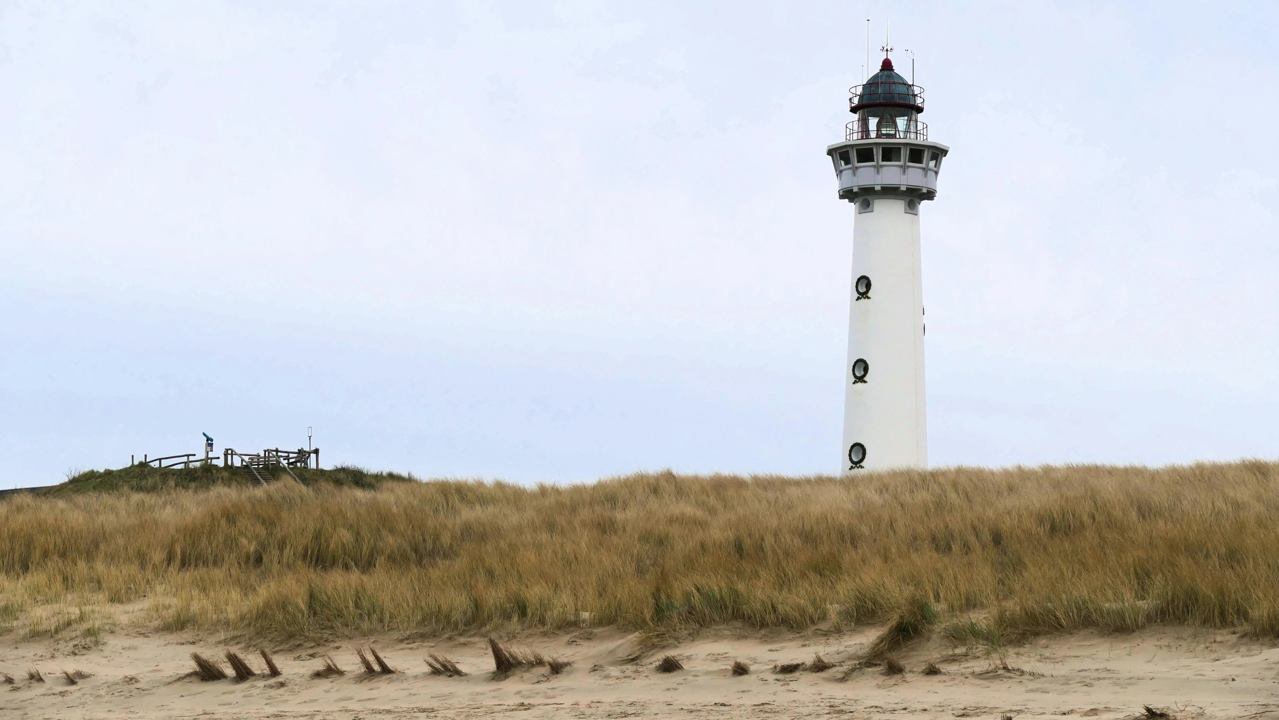 a lighthouse in the background and a dune in the foreground