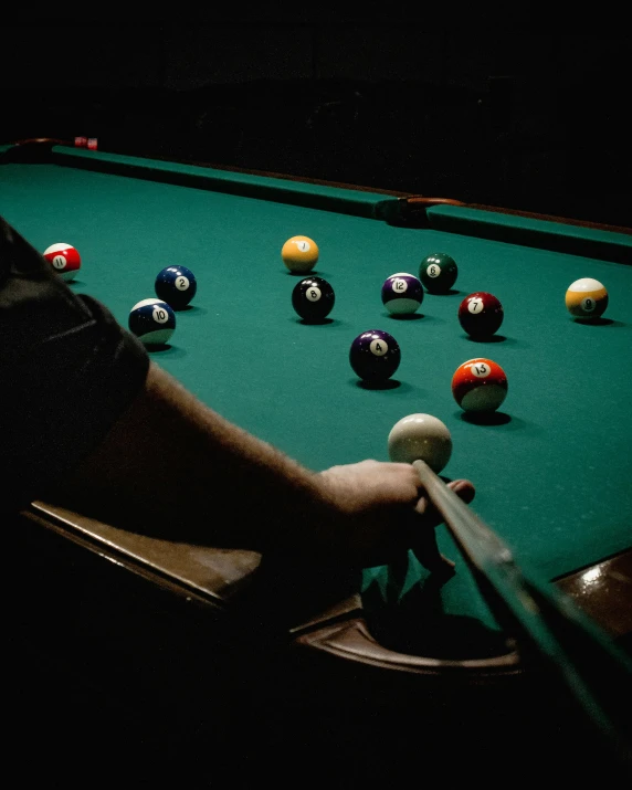 person leaning over a pool table while his hands hold the bill