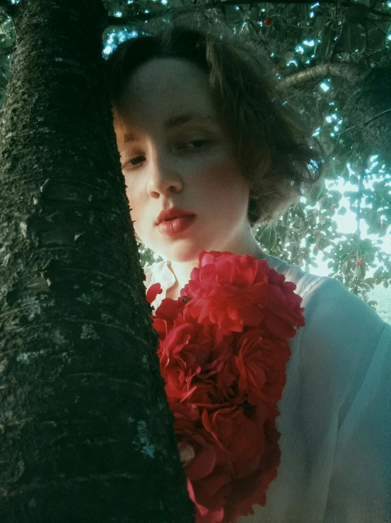 a woman is looking down behind a tree