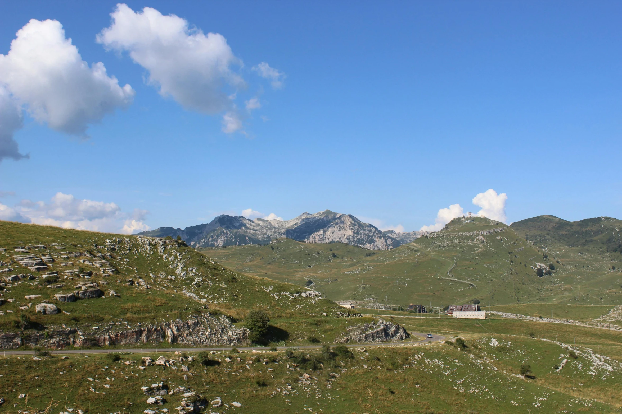 a scenic s of a hill with sheep grazing on the grass