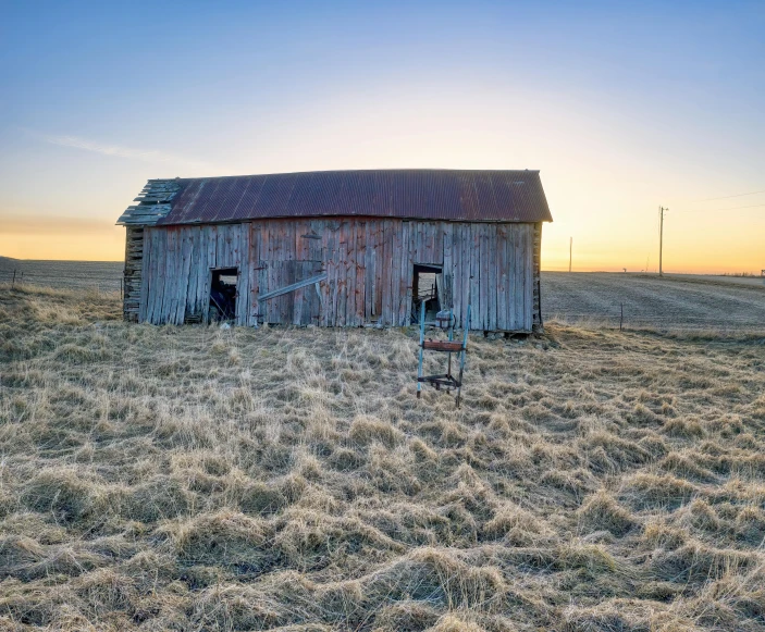 a barn in a grain field at sunset