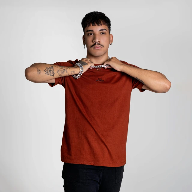 man with tattoos in an orange shirt looks up