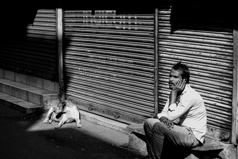 black and white image of a man sitting by a dog