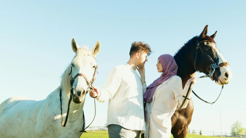 a man and woman standing next to each other with two horses