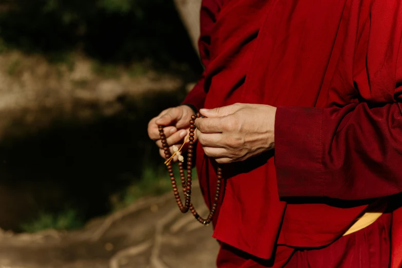 a woman wearing a red robe holds a chain in her hands