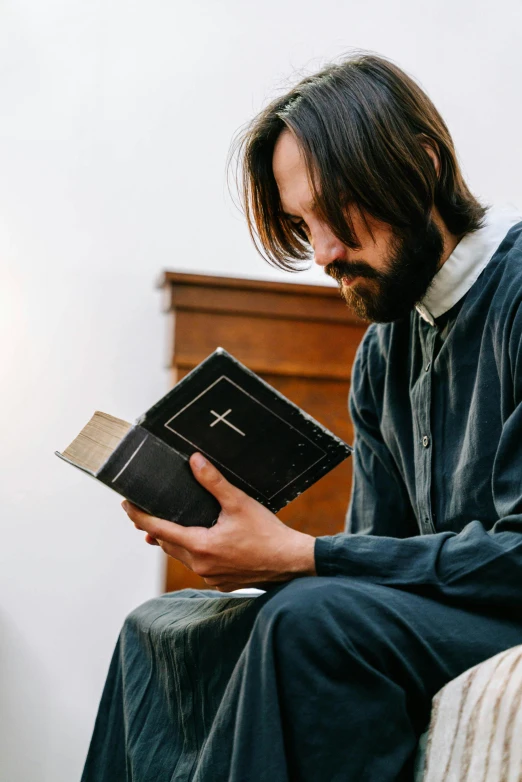 a man reading a book on top of a bed