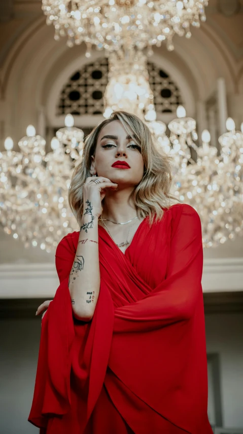 a beautiful woman in a red dress posing with her hand on her cheek