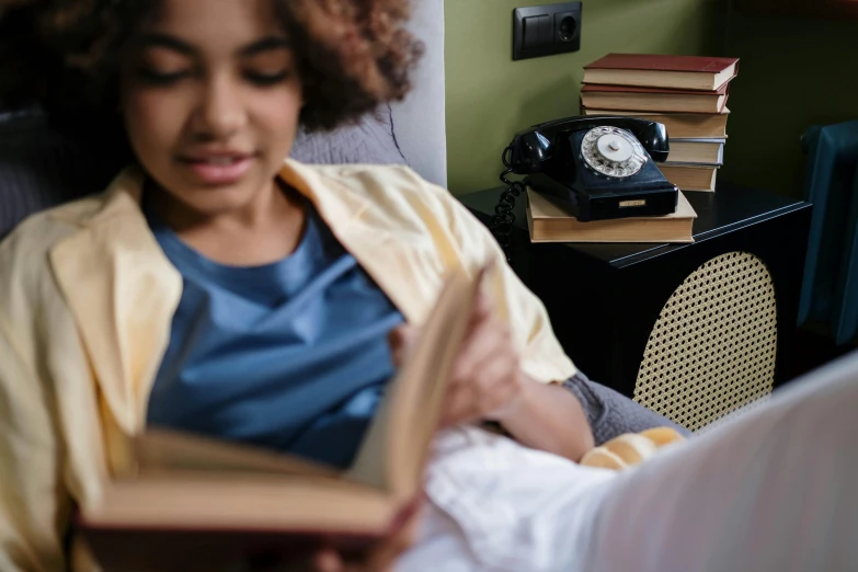 a woman is sitting on a couch while reading a book