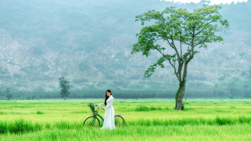 woman posing next to her bike in a green field