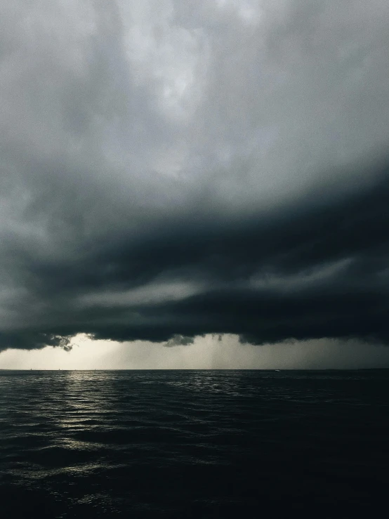 a plane flying over the ocean under a stormy sky