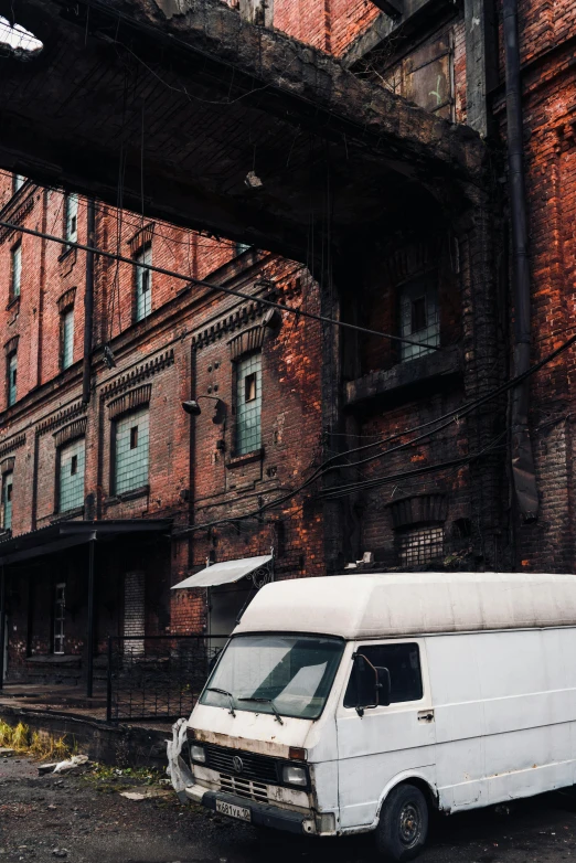 an abandoned van next to an old brick building