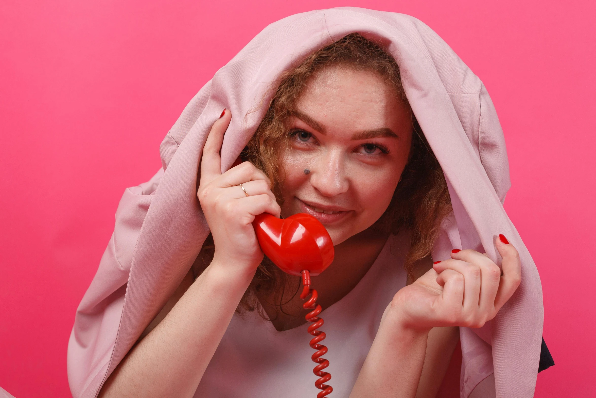 a woman in white shirt holding a red telephone