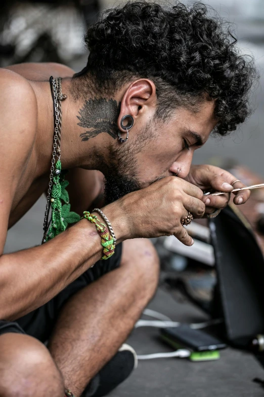 a man with a beard, piercing and tattoos on holding a pipe