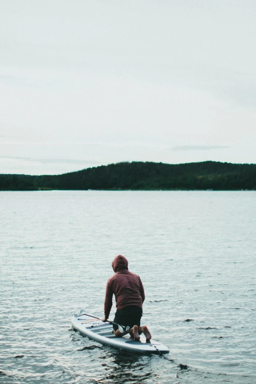 man in red jacket sitting on surfboard in the water