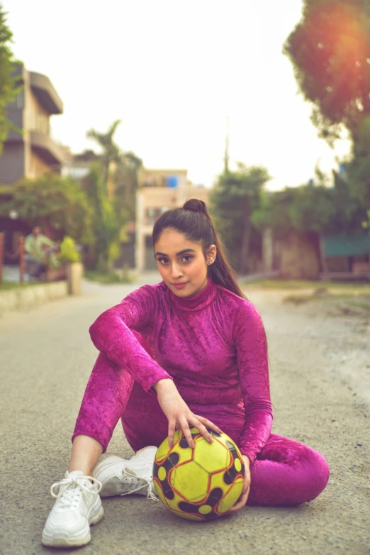 a girl in purple with soccer ball on the street